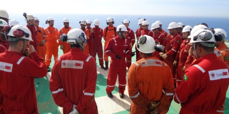 Trabalhadores da GranServices em círculo discutindo processos operacionais em plataforma offshore antes de iniciar o trabalho.