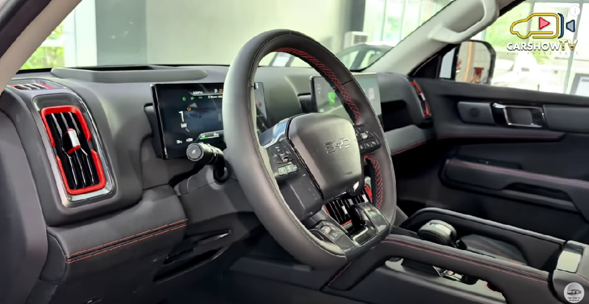 O painel da BYD Shark 2025 conta com uma tela digital de alta resolução que exibe informações como consumo híbrido, autonomia e modos de condução. Ele ainda permite ajustes no ar-condicionado e na regeneração de freios, mas depende excessivamente da central multimídia, dificultando o acesso rápido a funções básicas.