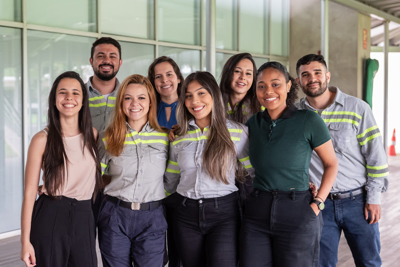Grupo de jovens estagiários da Tenaris sorrindo, representando o Programa de Estágio 2025.2, em um ambiente corporativo moderno.