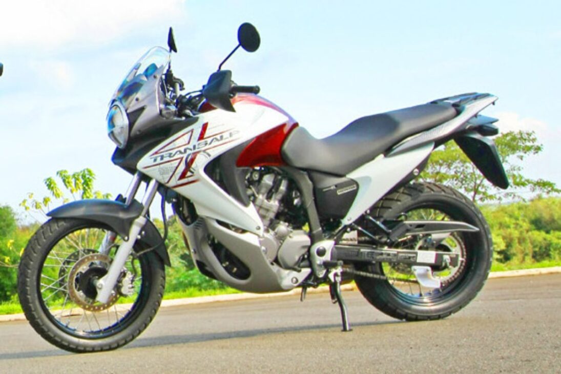 No mercado brasileiro de motocicletas, poucas histórias são tão curiosas quanto a da Honda XL 700V Transalp. Apresentada no Brasil em 2011, a moto teve uma passagem discreta e encerrou suas vendas em 2014, sem deixar saudades nos relatórios financeiros da marca. Equipada com um motor V-Twin de 680cc cheio de personalidade, ela chegou como uma proposta de equilíbrio, mas o mercado da época não a compreendeu.