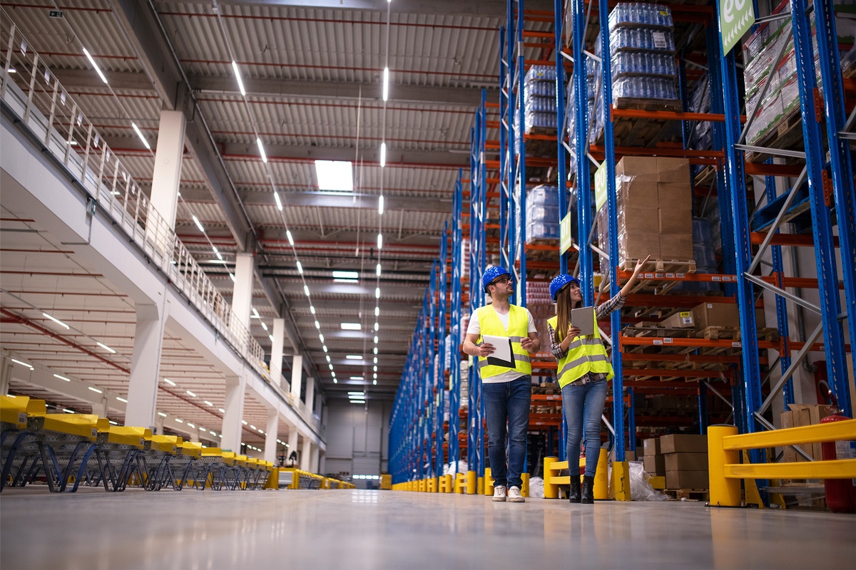 Funcionários inspecionam prateleiras em centro logístico moderno