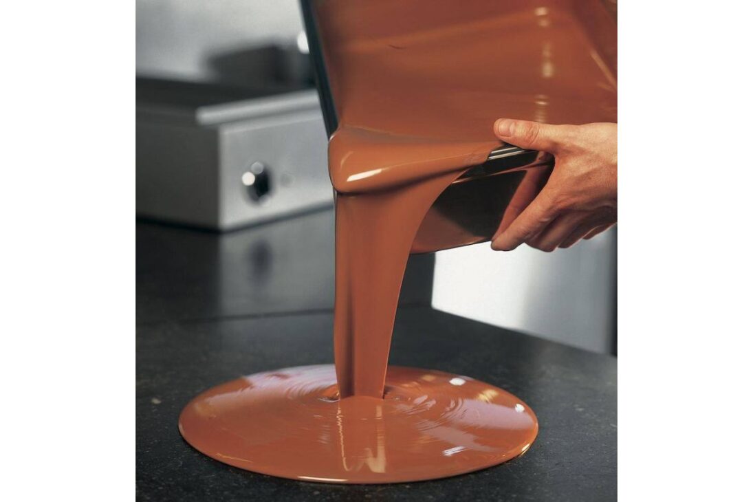 Esta é a etapa mais crítica e científica de todo o processo. A manteiga de cacau, a gordura natural do cacau, pode se solidificar em seis formas diferentes de cristais. Apenas uma delas, a estável "Beta V", resulta em um chocolate que é brilhante, firme, que quebra com um estalo seco característico (o "snap") e que não derrete facilmente ao toque.