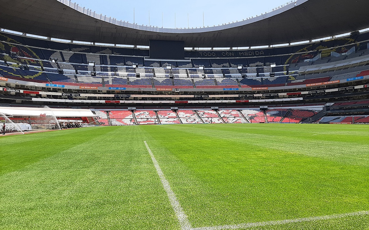 Estádio de futebol com gramado verde visto do centro do campo vazio