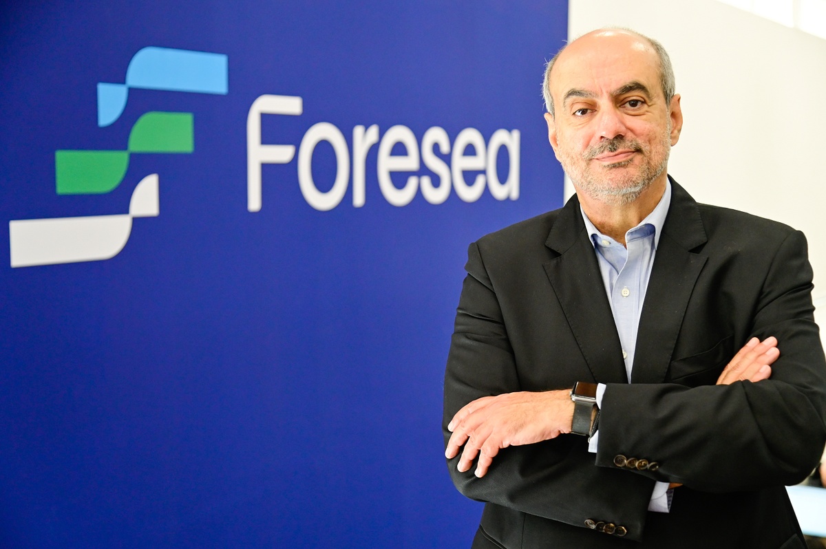 Rogerio Ibrahim, CEO da Foresea, posa com braços cruzados em frente à logomarca da empresa.