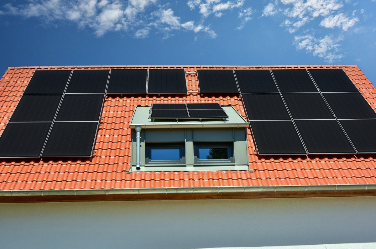 Painéis solares instalados em telhado de casa residencial sob céu azul claro