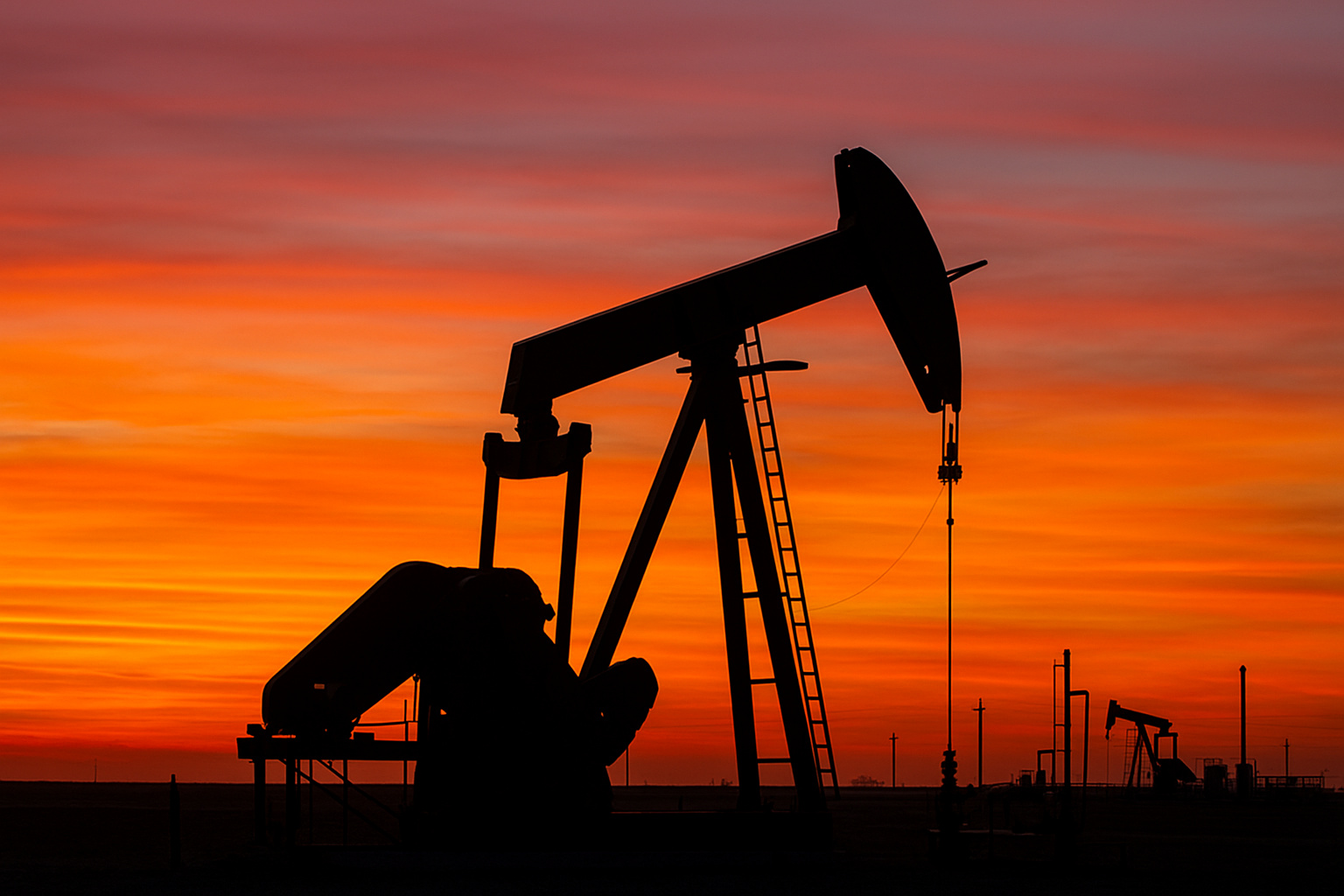 Bomba de petróleo operando ao entardecer, simbolizando o impacto da guerra e da Opep+ no mercado energético