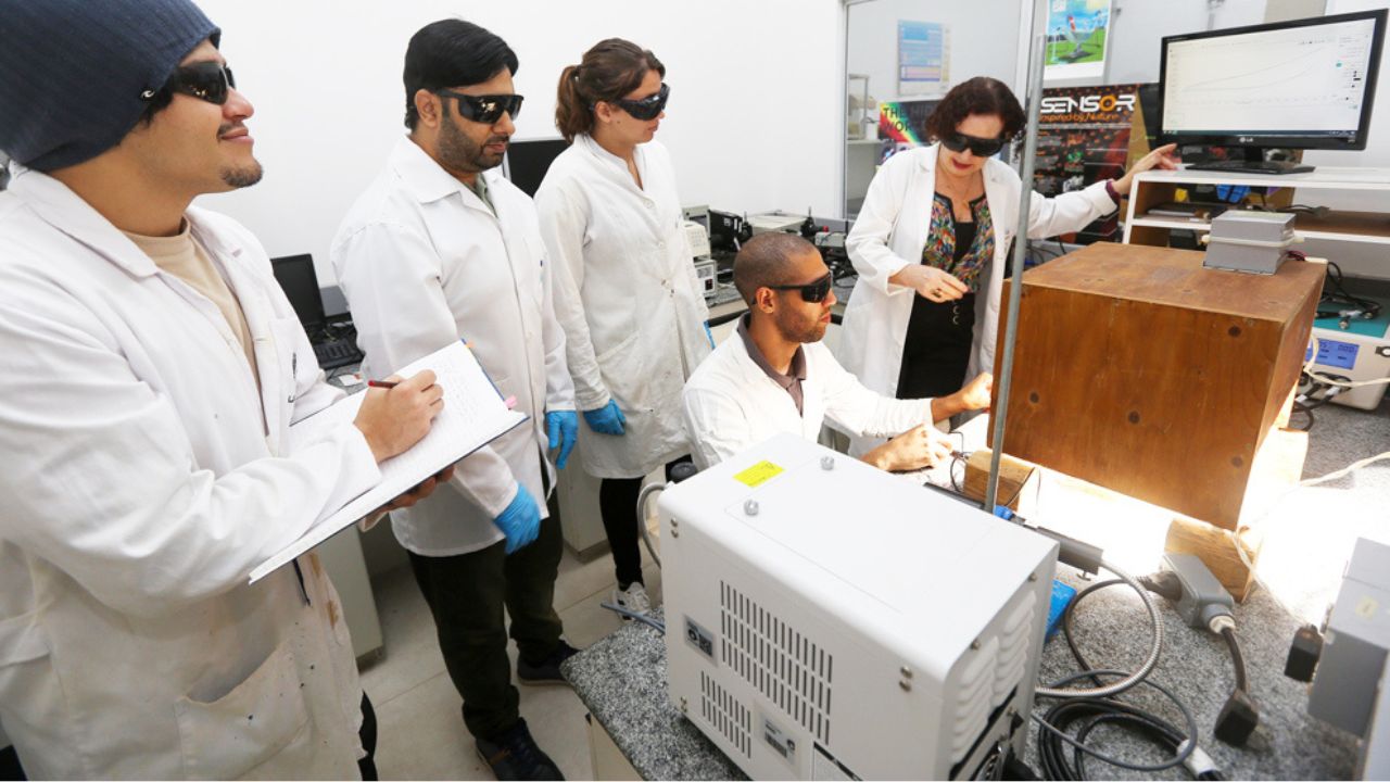 Grupo de pesquisadores em laboratório da Unicamp operando equipamentos científicos e analisando dados em ambiente de pesquisa colaborativa
