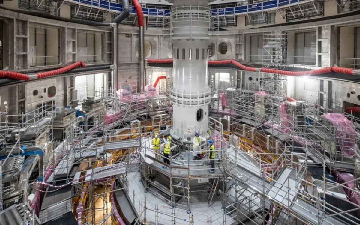 Engenheiros trabalham na montagem do núcleo de um reator de fusão nuclear na França, em ambiente industrial moderno e altamente tecnológico.