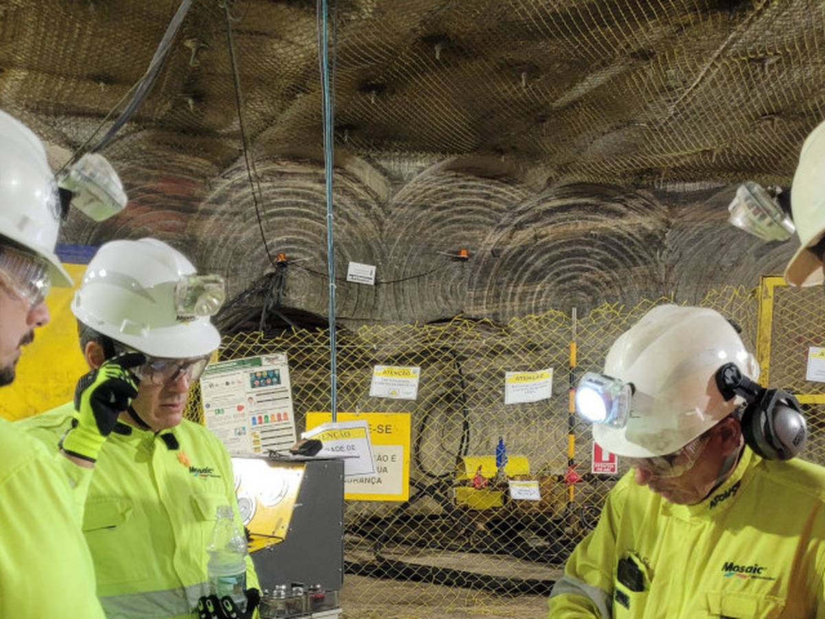 Trabalhadores em mina de potássio da VL Holding em Sergipe, equipados com capacetes e uniformes de segurança durante inspeção subterrânea.