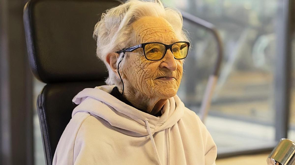 Idosa de 101 anos usando óculos amarelos em academia enquanto treina, representando longevidade, rotina ativa e hábitos saudáveis.