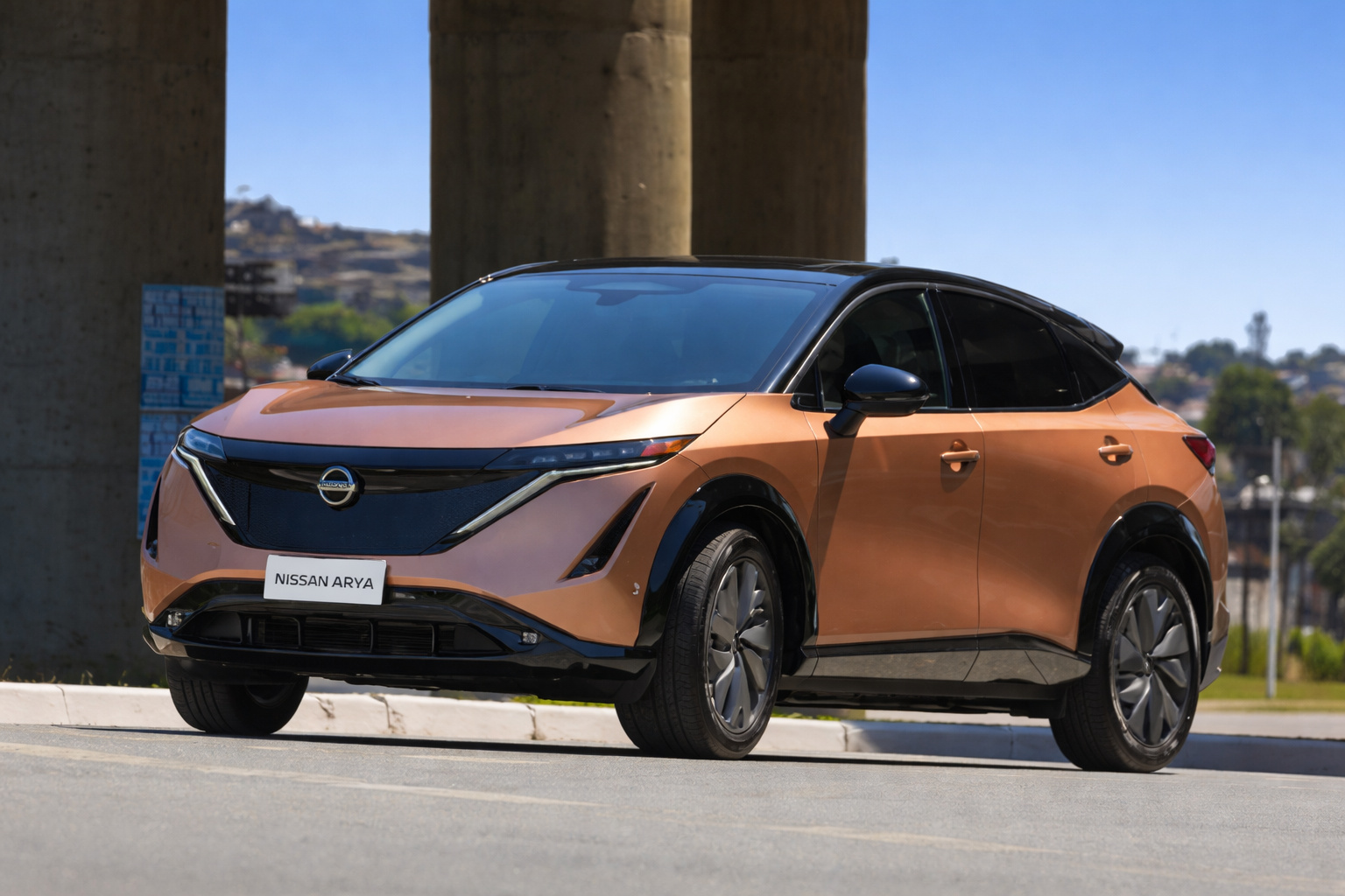 Carro elétrico Nissan Ariya estacionado em área urbana, sob viaduto, com céu azul limpo ao fundo.
