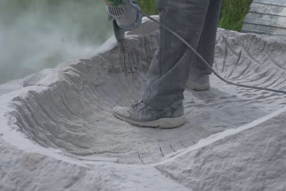 A banheira de pedra esculpida à mão a partir de granito e de uma rocha de 23.000 libras consumiu meses, muitos disco de corte e polimento e uma rotina intensa contra poeira, riscos e lesões em oficina ao ar livre.