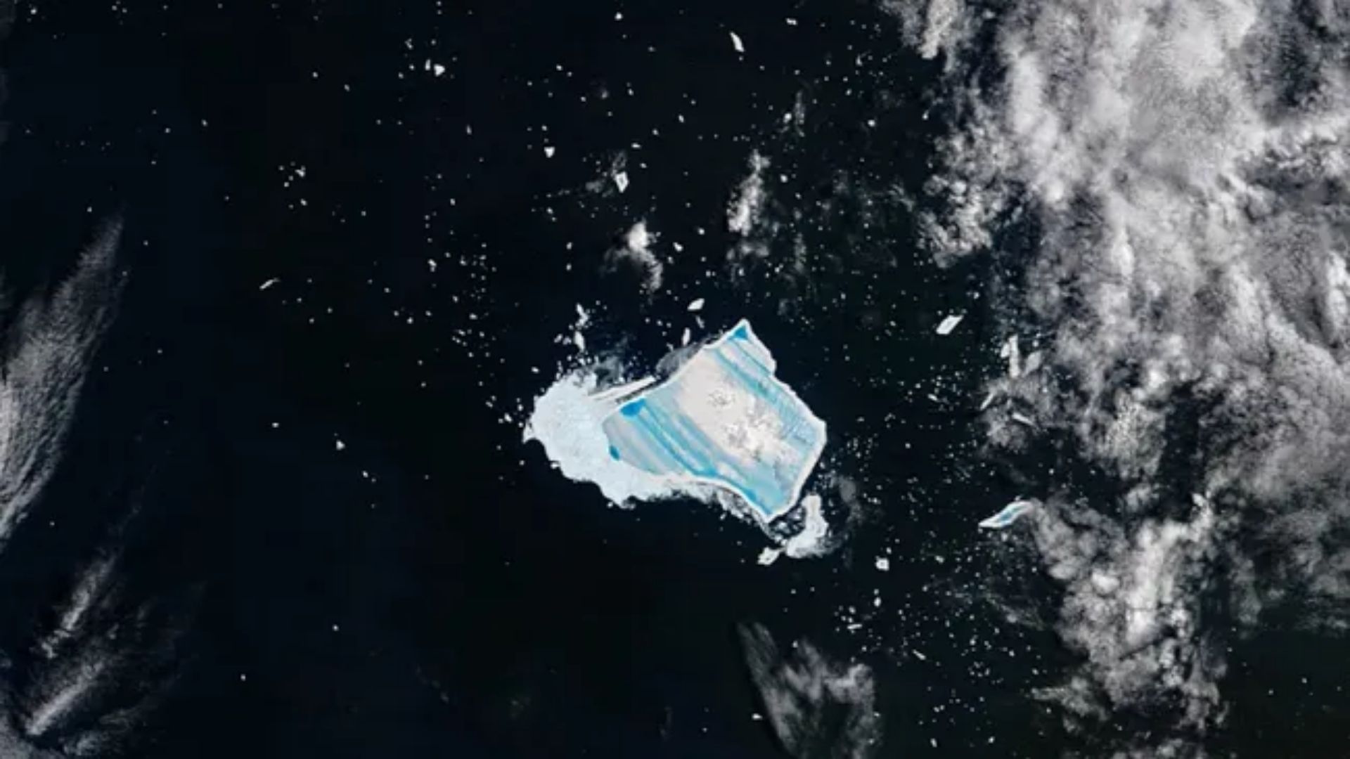 Mega-iceberg A23a fragmentado no Atlântico Sul com lagos de degelo azul visíveis do espaço.