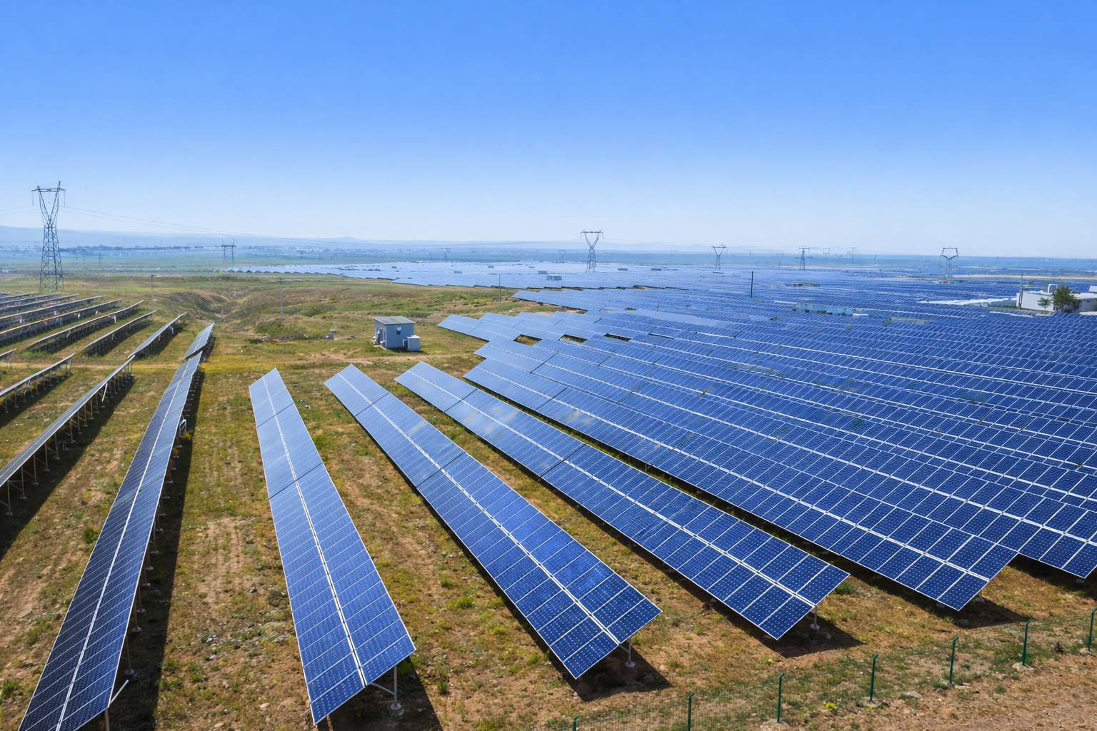 Vista aérea de uma usina solar com painéis fotovoltaicos alinhados sob céu azul em pleno meio-dia.